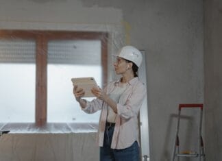 Nowe technologie w budownictwie jednorodzinnym, które przyspieszają budowę i obniżają koszty wykończenia Architektka w kasku analizuje projekt domu na tablecie w stanie surowym