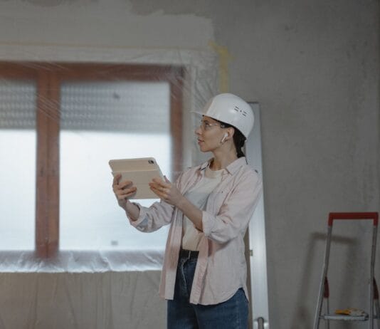 Nowe technologie w budownictwie jednorodzinnym, które przyspieszają budowę i obniżają koszty wykończenia Architektka w kasku analizuje projekt domu na tablecie w stanie surowym